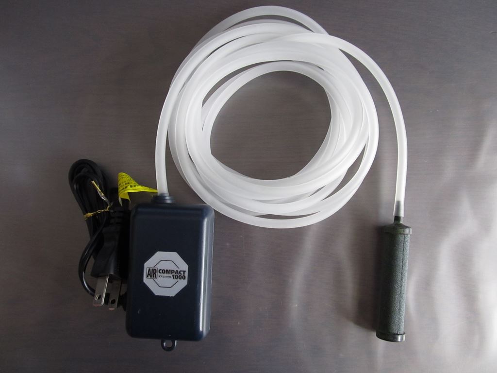 Aquarium air pump connected by tubing to a cylindrical air stone